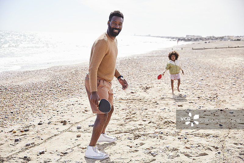 一个父亲和他的儿子在海滩上玩耍的快速肖像，转向相机快速快照。图片素材