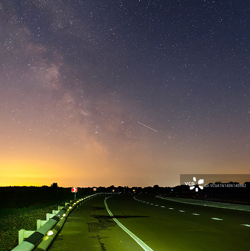 沥青路转弯下星空下星空下银河，夜间交通基础设施场景图片素材