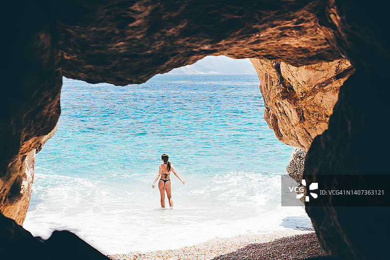 女人放松在小，空，秘密的海滩与洞穴。图片素材