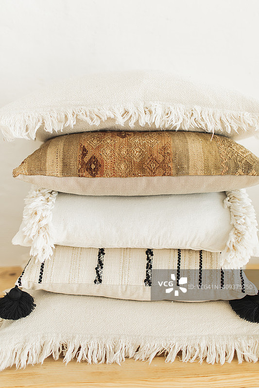 波西米亚风格的枕头靠在白墙背景的木椅上。图片素材