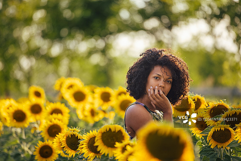一个卷发女人的肖像，站在向日葵周围图片素材