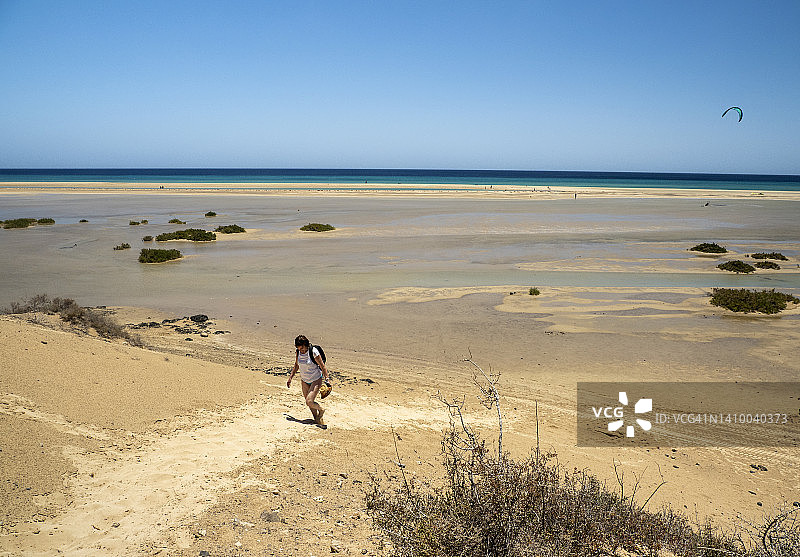 一个女人走在清澈的浅滩上。图片素材