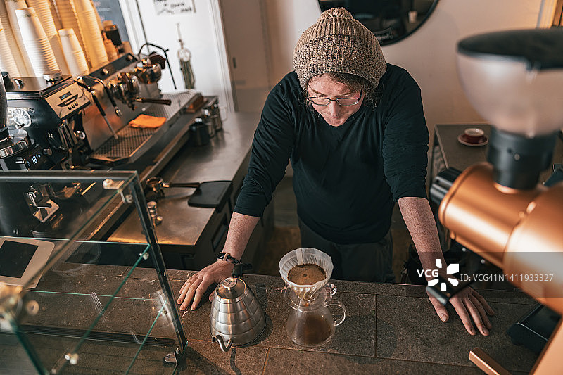男咖啡师站在咖啡店的柜台上制作滴滤咖啡图片素材