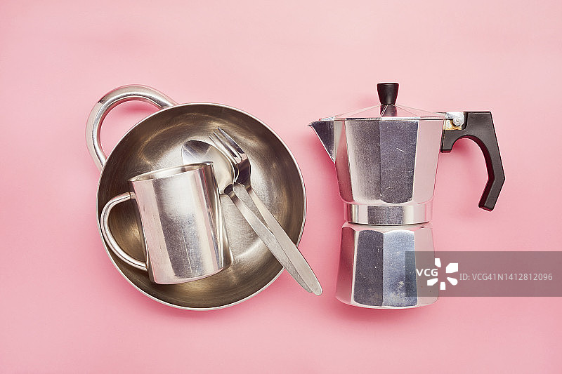 静物的一个杯子，餐具，盘子和一个炉顶咖啡壶在粉红色的背景图片素材