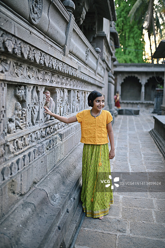 一个可爱的小女孩在一座古老的寺庙里观察石雕图片素材