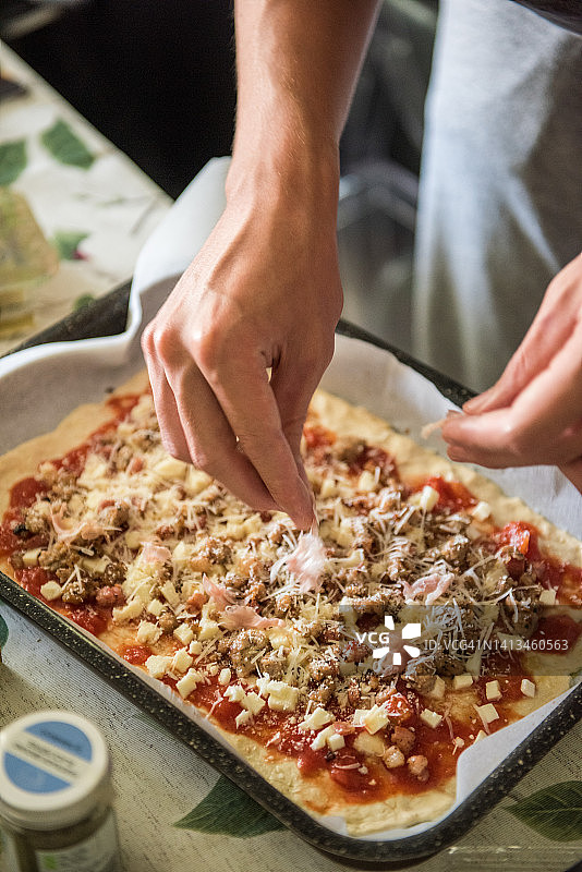在火腿和香肠的quattro formaggi披萨上添加配料图片素材