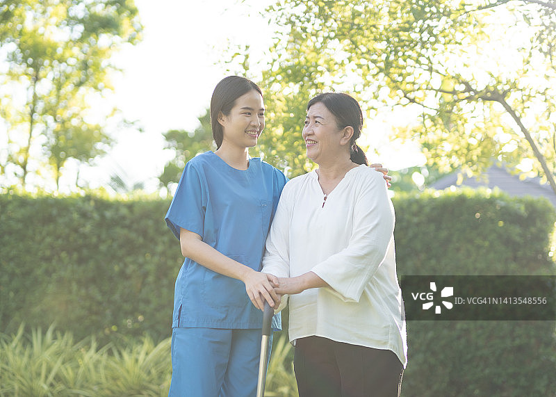 亚洲女护士协助幸福女老年病人在她的家里坐轮椅图片素材