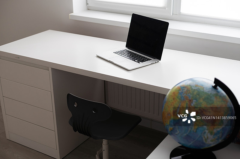 现代工作空间与白色桌面白色墙壁背景的黑屏笔记本电脑图片素材