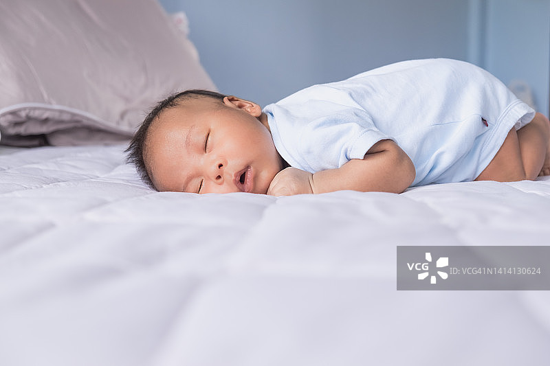 放松可爱的亚洲新生男婴躺在快速睡眠图片素材