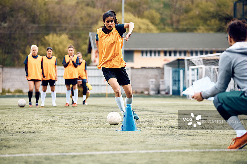 女足球运动员在运动训练中在视锥细胞中带球。图片素材