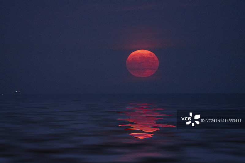 满月的橙色月亮升起在海上图片素材