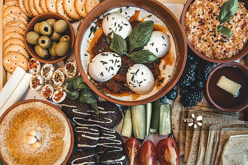 平铺:传统的阿拉伯早餐，鸡蛋，橄榄，鹰嘴豆泥，皮塔饼，蔬菜，沙拉三明治，蜂蜜，菲达奶酪。图片素材