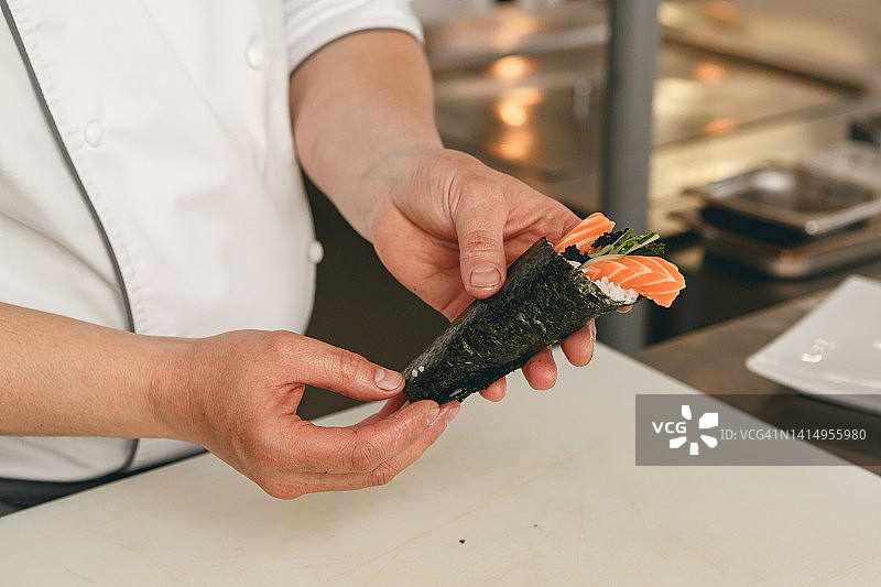日本餐厅厨房，厨师用米饭、三文鱼和海苔制作寿司图片素材