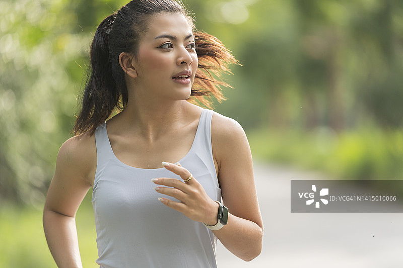 一名亚洲女子在日落时分慢跑锻炼。图片素材