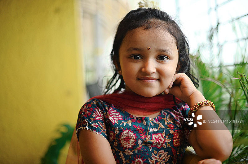 一个可爱的印度女孩穿着传统服装站在阳台上的肖像图片素材