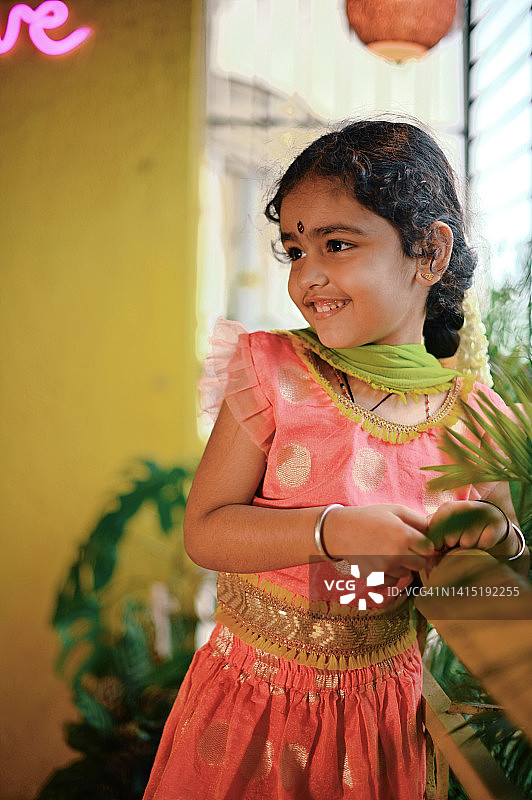 可爱的印度女孩穿着传统服装站在阳台上的肖像图片素材