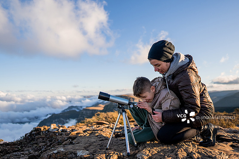 母亲和儿子在山顶上用望远镜观察图片素材