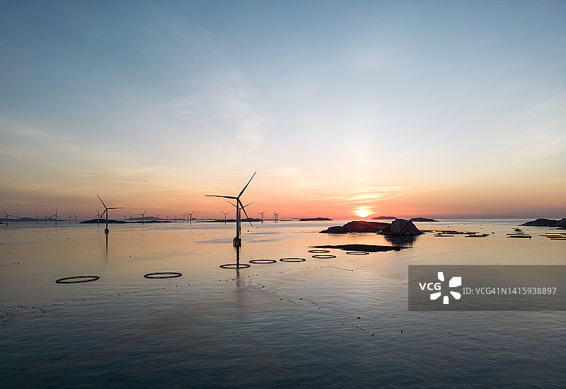 风力涡轮机和渔场在日出时在海上图片素材