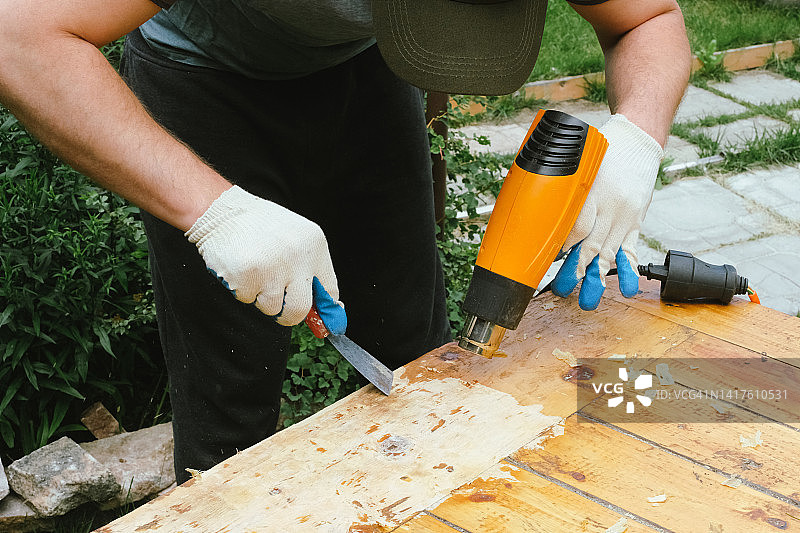 用刮板和热风枪清除木头上的旧清漆。图片素材
