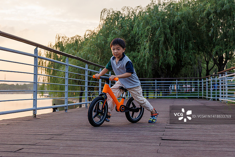 这个小男孩在公园里骑自行车图片素材