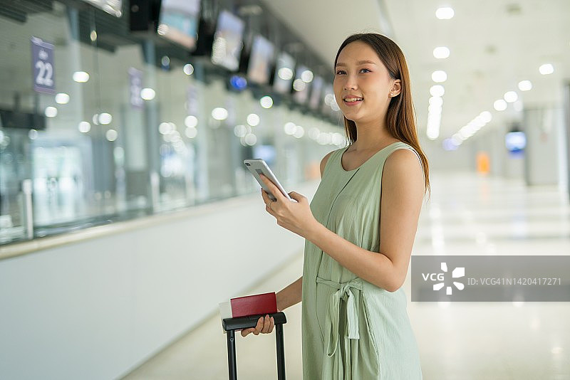 一个年轻的亚洲女性的肖像照片与她的手机和行李箱准备和去她的梦想的度假目的地旅行图片素材