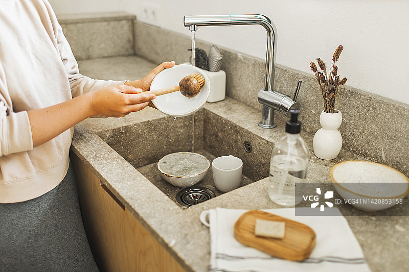 女人的手用天然刷子洗碗。可持续生活，零浪费图片素材
