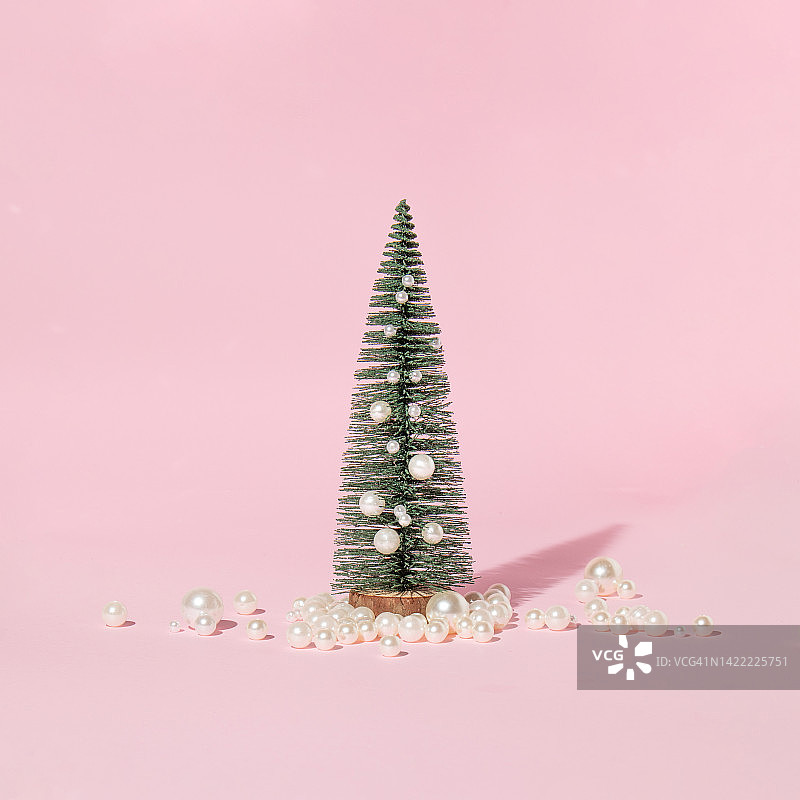 创意布局与圣诞树和白色珍珠在柔和的粉色背景。浪漫的新年概念。最小的圣诞假期想法。图片素材