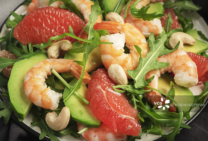 健康新鲜的沙拉配虾，牛油果，柚子，芝麻菜和腰果。近距离图片素材
