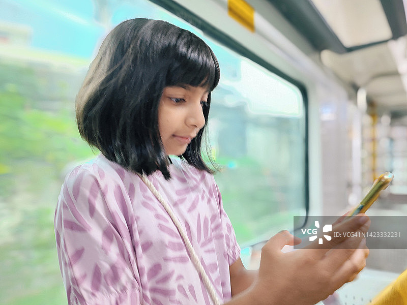 一个可爱的女孩在火车上使用手机图片素材