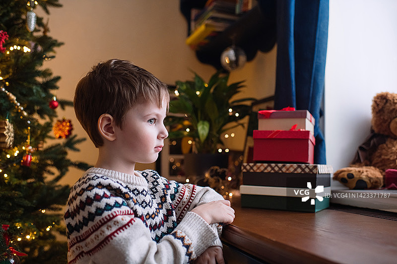 圣诞假期，小男孩若有所思地望着窗户图片素材