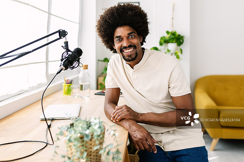 画像微笑的美国黑人年轻男子坐在家里工作室-快乐的企业家男性看着相机在工作场所图片素材