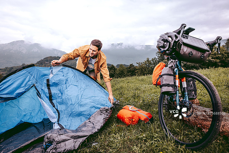 年轻英俊的男子在野外搭起帐篷露营图片素材
