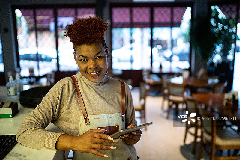 肖像的女服务员使用数字平板电脑在餐厅图片素材
