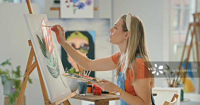 有创意的女艺术家在艺术工作室用画笔在画布上绘画。手持调色板，用水彩和油画画花朵肖像的专业艺术家或画家图片素材
