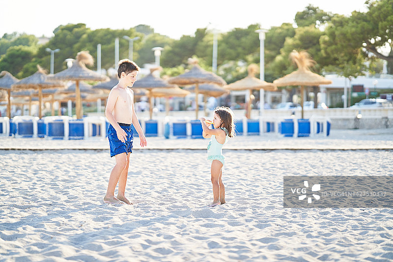 小女孩和她的哥哥在海滩上享用冰淇淋。图片素材