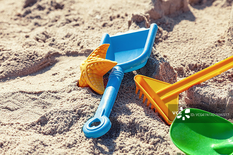阳光明媚的日子，沙滩上五颜六色的塑料铲图片素材