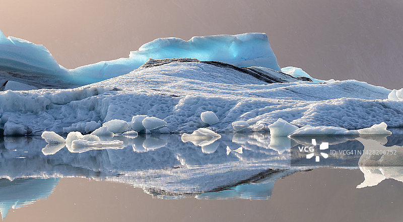 阿拉斯加尼克冰川底部的冰山被清晨的阳光照得背光图片素材