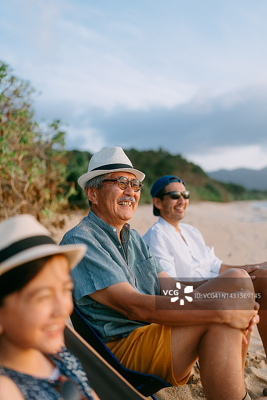 快乐的老人与家人在海滩上享受日落图片素材