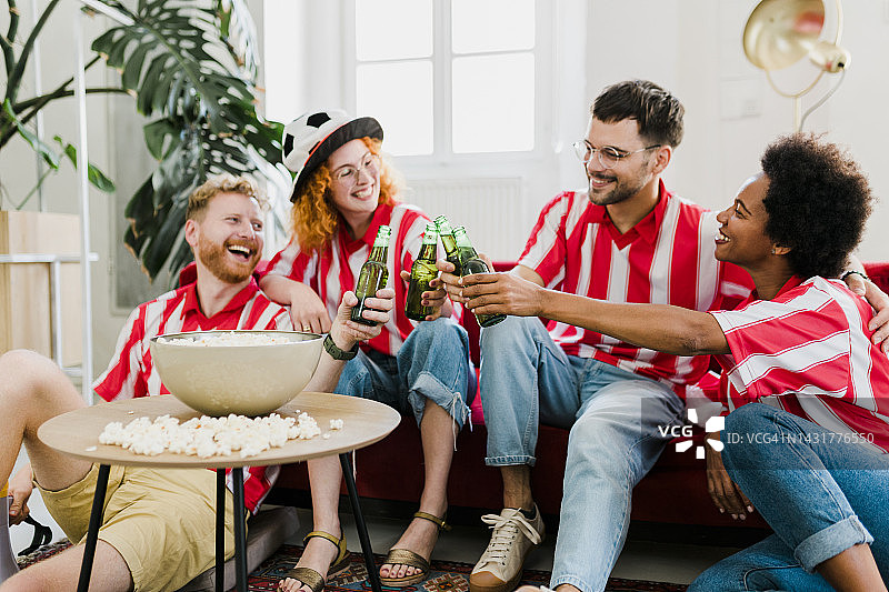 一群欢呼的人吃着爆米花，喝着啤酒，看电视上的足球比赛，在他们的球队进球后庆祝胜利图片素材