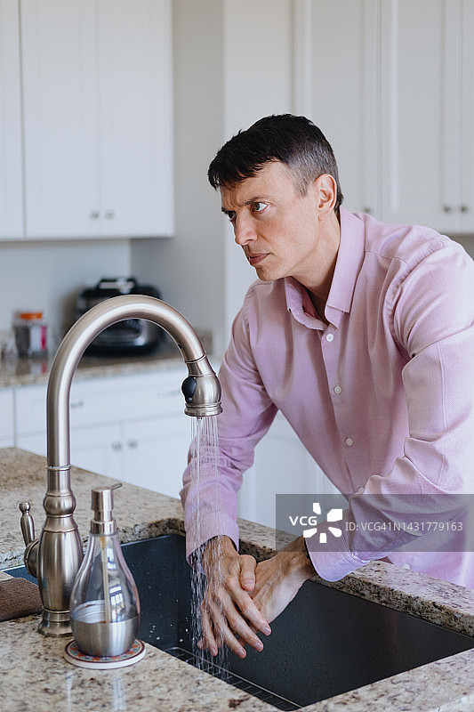 男子在厨房水槽洗手图片素材