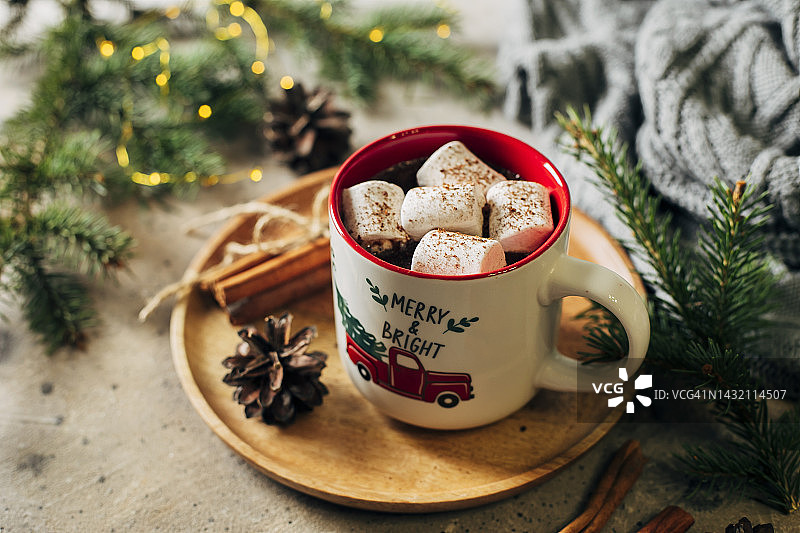 热巧克力，棉花糖和拐杖糖在节日马克杯。杉树树枝，舒适的灰色毛衣背景。舒适的季节性圣诞假期概念图片素材