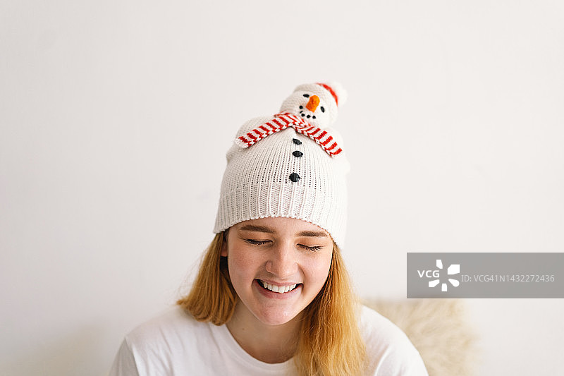 有趣的小女孩，戴着圣诞帽，堆着雪人，围着红色围巾。图片素材
