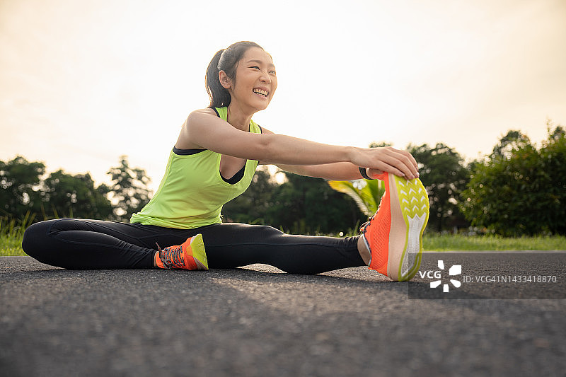 女性在跑步或锻炼前做热身运动。年轻的女性跑步者在晨跑前伸展手臂和腿部肌肉。健身和健康的生活方式理念。图片素材