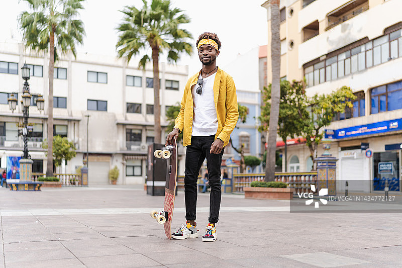 一个年轻的非洲人拿着滑板站着图片素材