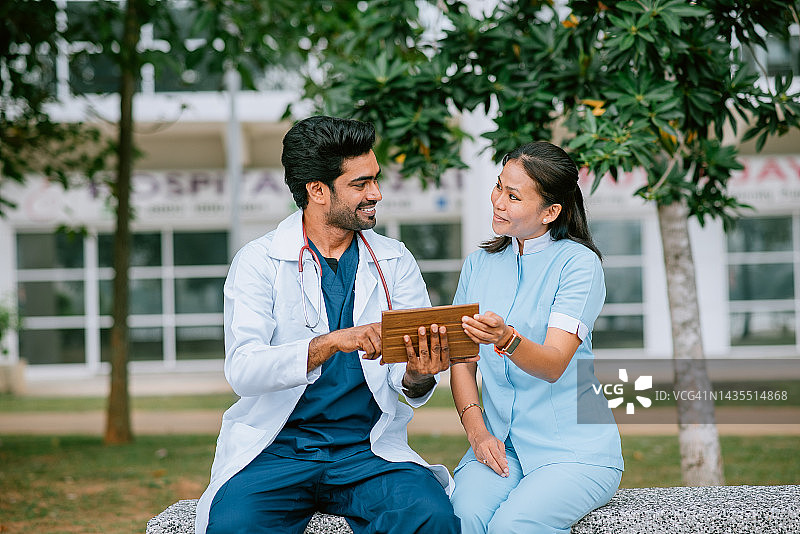 亚裔印度男医生和马来女护士正在用Ipad看病人报告图片素材