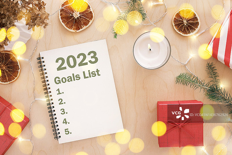 新年目标。2023待办事项清单写作。写在空笔记本木桌子与圣诞装饰。前视图。制定目标清单和决心。新生活，开始，开始的概念。经营理念图片素材
