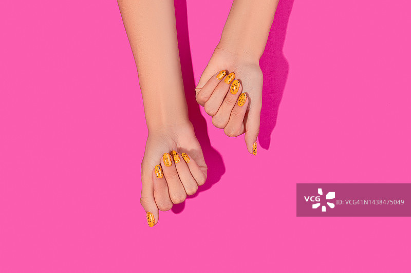 修剪整齐的女人的手与时髦的指甲设计的粉红色背景图片素材