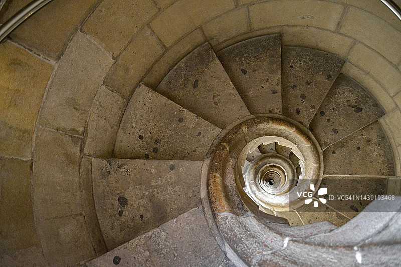 塔中古色古香的螺旋石蜗牛楼梯俯视图。走下古老的蜿蜒的楼梯。背景图片素材
