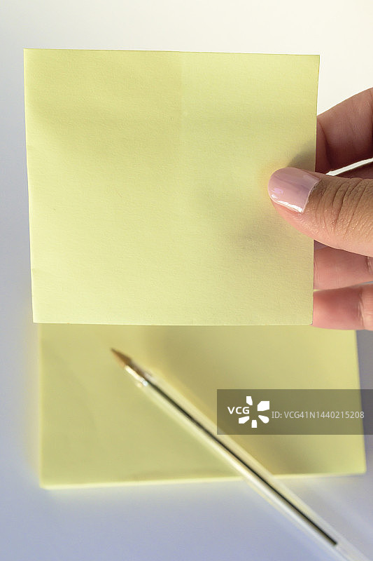 女人的手，涂了指甲拿着空白信纸在纯白色的背景图片素材