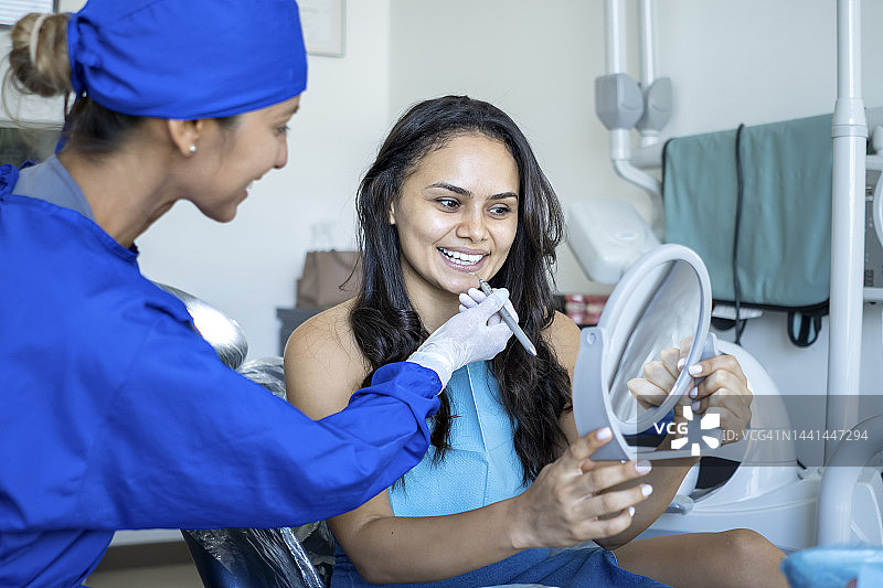 美丽的女人在治疗后检查她的牙齿。图片素材